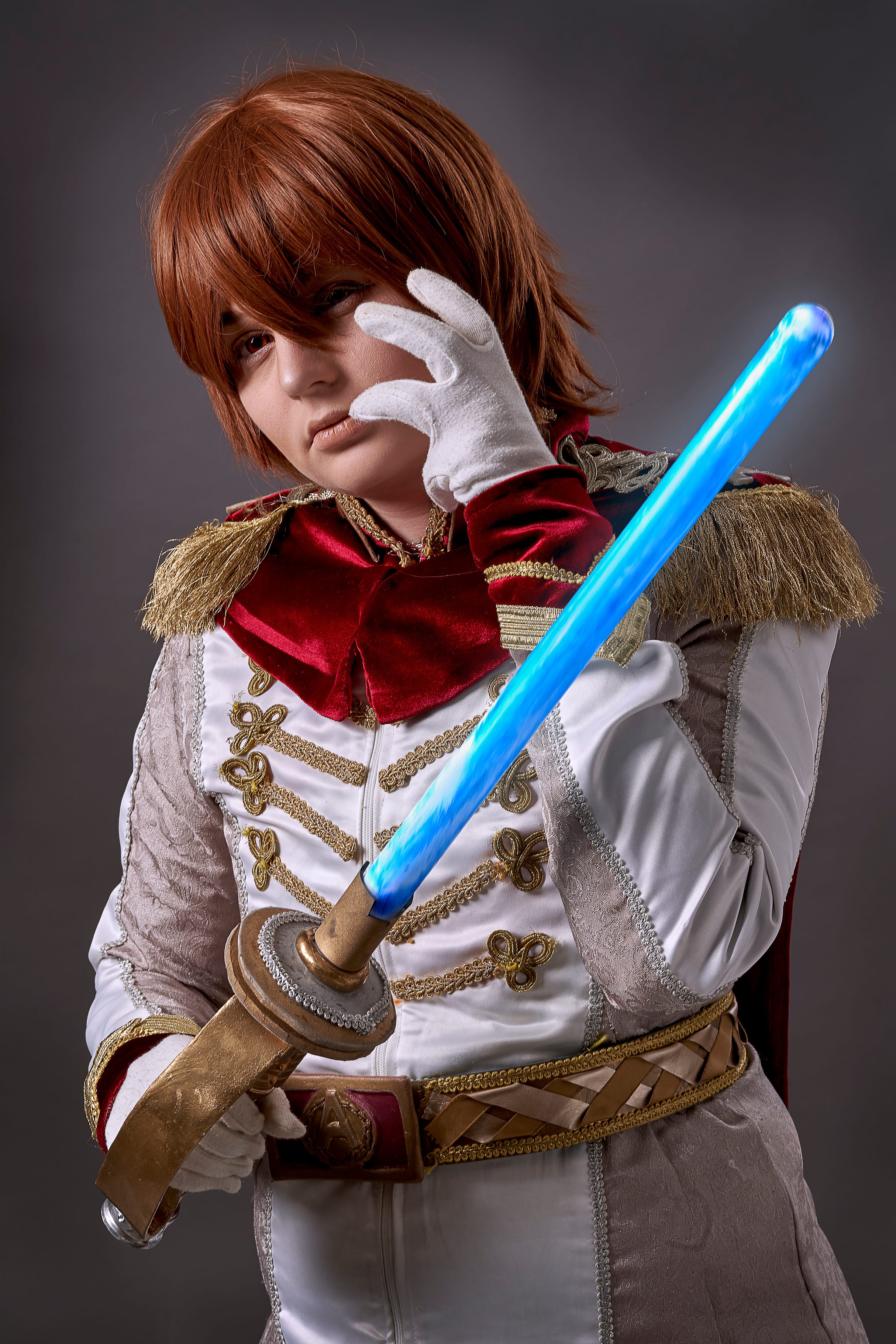 Cosplayer in an ornate white and red costume holding a blue illuminated sword