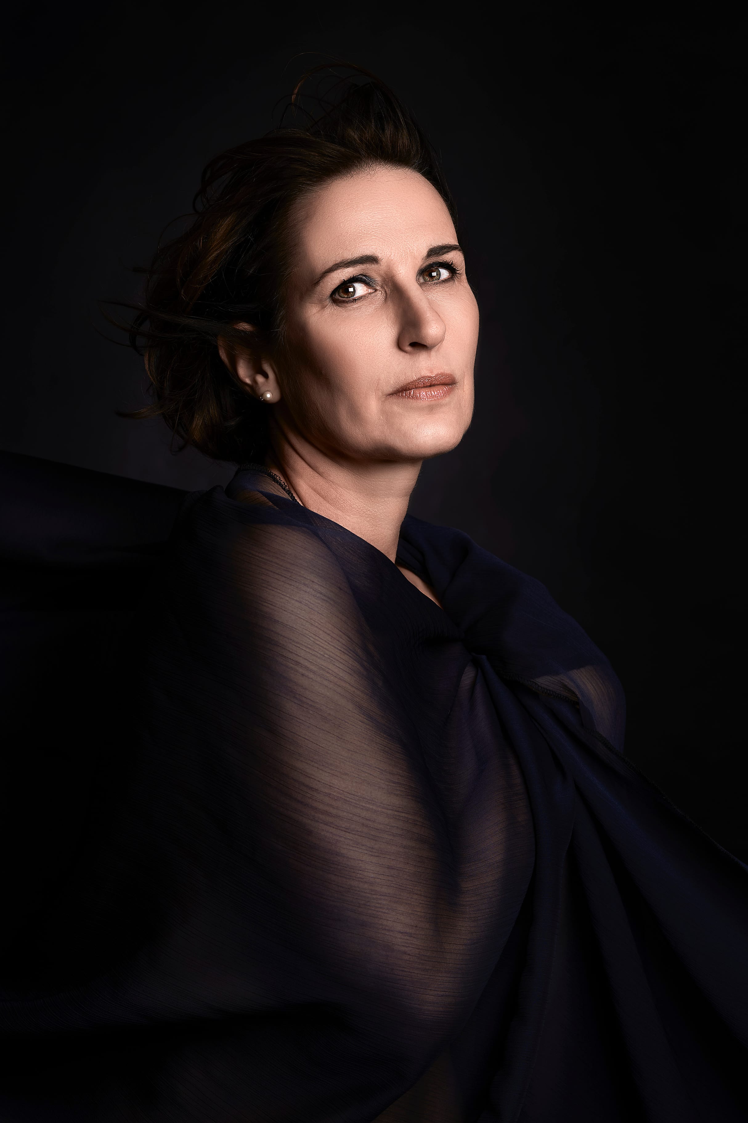 Iranian woman in dark translucent fabric, lit like a classical painted portrait
