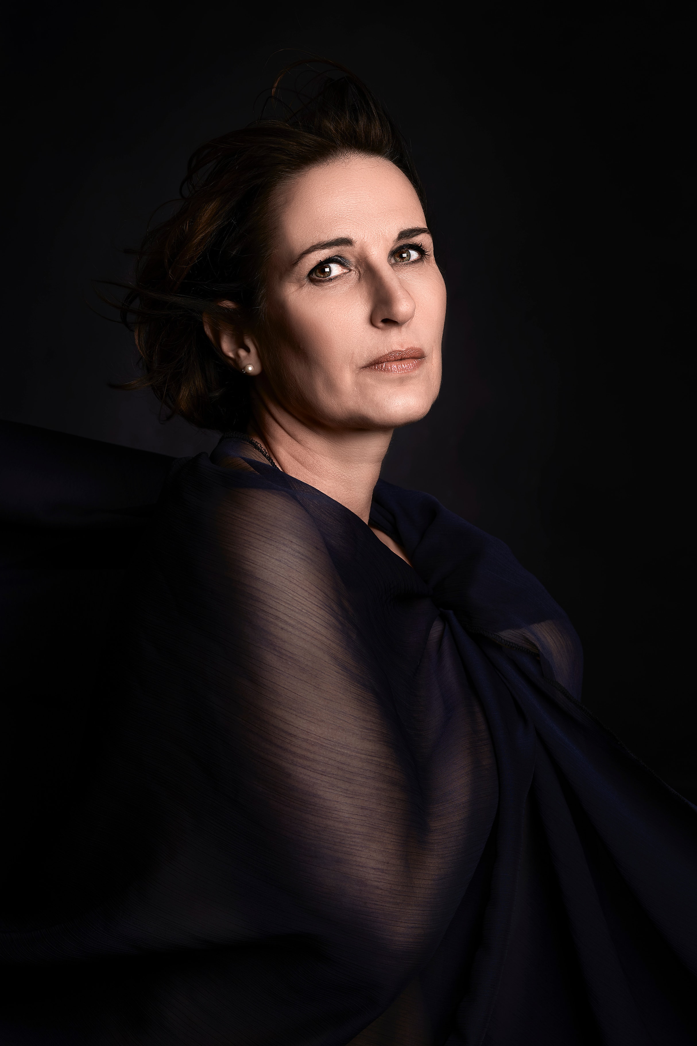 Iranian woman in dark translucent fabric, lit like a classical painted portrait