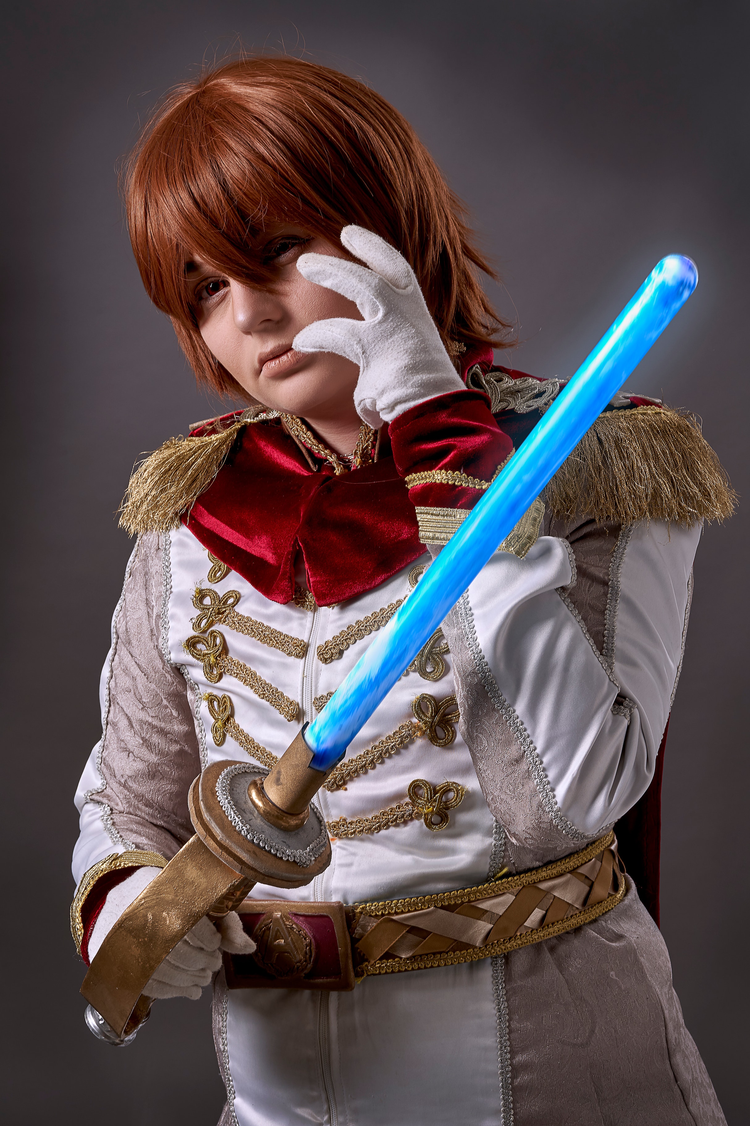 Cosplayer in an ornate white and red costume holding a blue illuminated sword